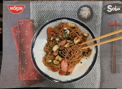 Classic chicken with smoked chicken sausage, garlic courgette, bok choi leaves and spring onion. With chopsticks on placemat.
